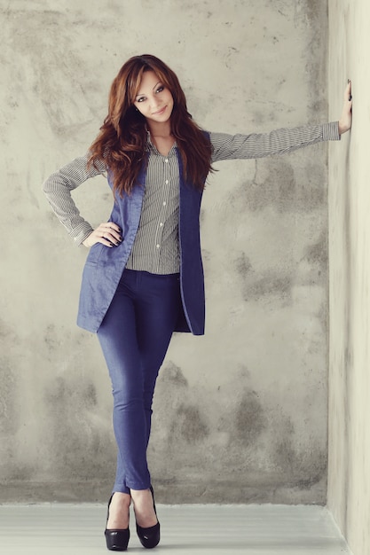 Elegant businesswoman posing on concrete wall