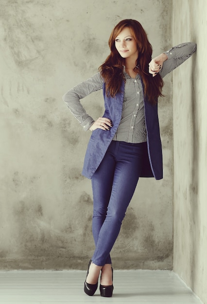 Elegant businesswoman posing on concrete wall