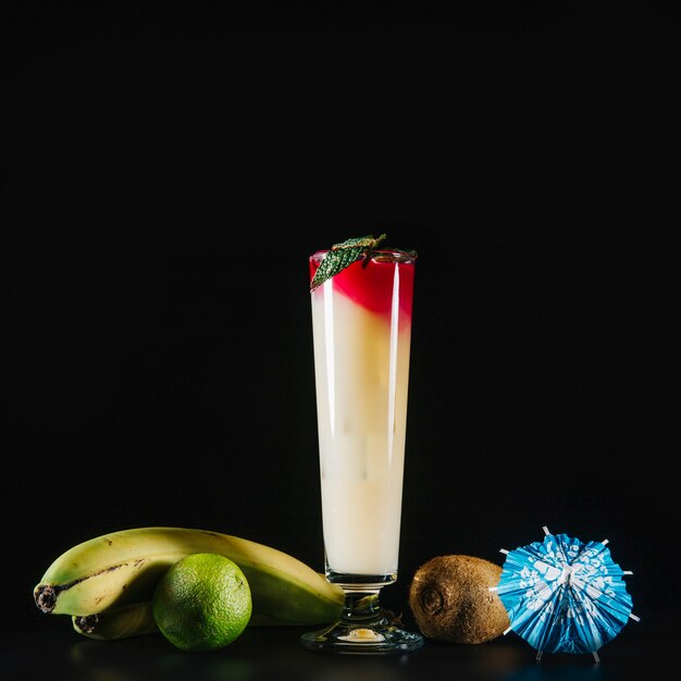 Elegant cocktail and exotic fruits on black background