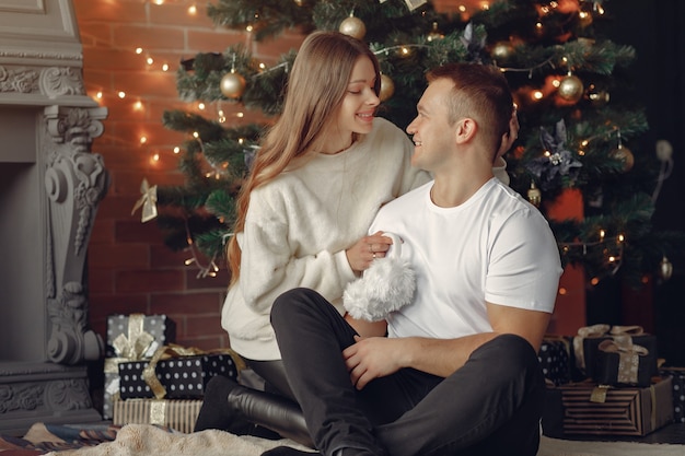 Elegant couple sitting at home near christmas tree