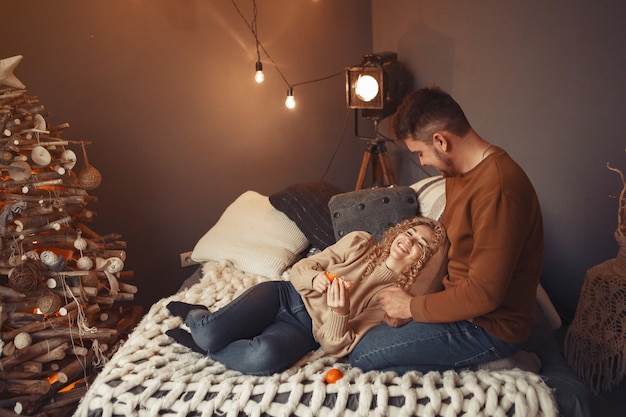 Free photo elegant couple sitting at home near christmas tree