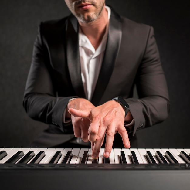 Free photo elegant dressed man playing digital keyboards