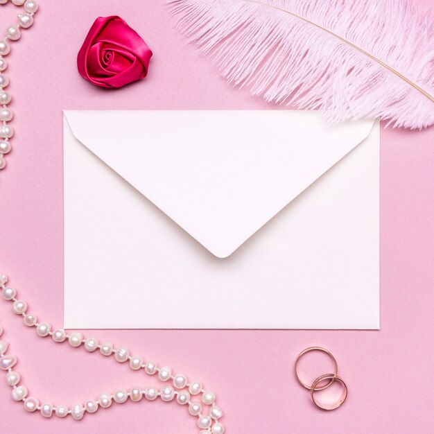 Elegant envelope surrounded by pearls and wedding rings