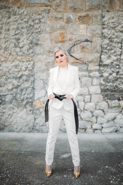 Free photo elegant fashionable female in a white suit with black belt and pants posing for fashion photoshoot