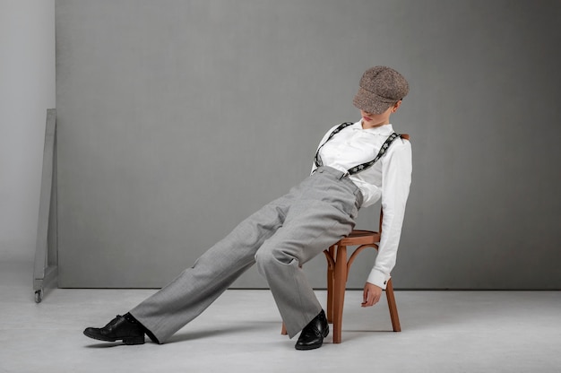 Free photo elegant female model posing in a chair in elegant white shirt and suspenders. new feminity concept