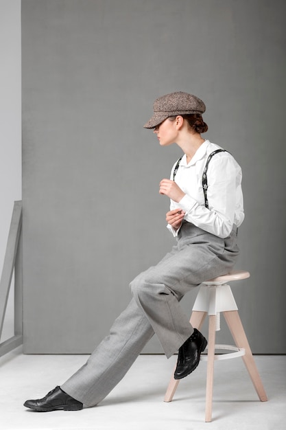 Elegant female model posing in a stool in elegant white shirt and suspenders. new feminity concept