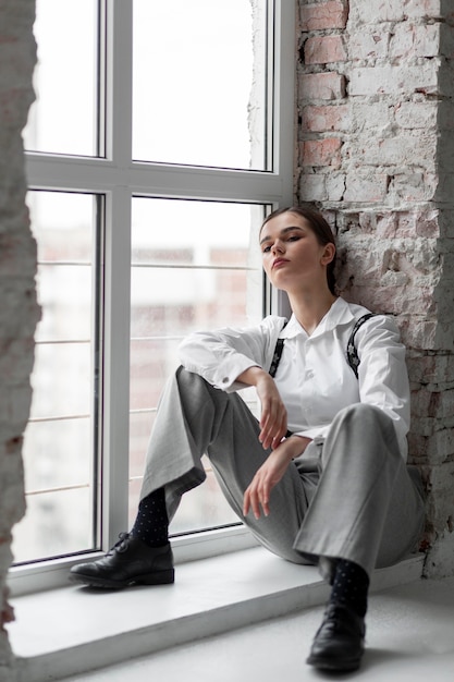 Free Photo elegant female model posing in a window in elegant white shirt and suspenders. new feminity concept