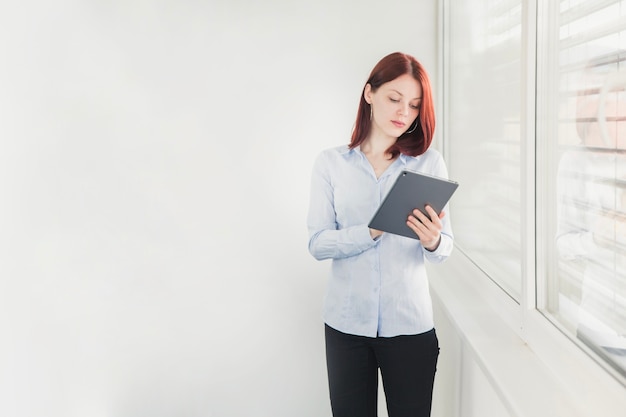 Free photo elegant female worker browsing tablet