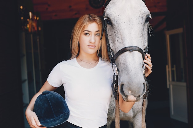 Elegant girl in a farm wiith a horse