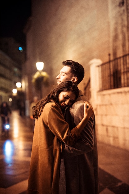 Elegant happy woman hugging with young man on promenade at night