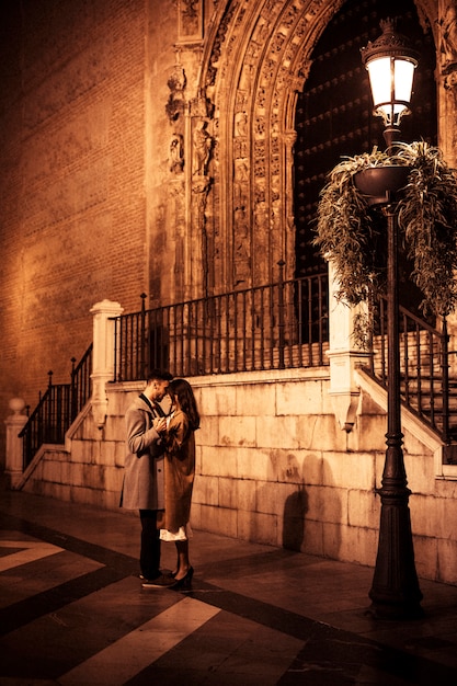 Elegant lady hugging and holding hands with young guy on street 