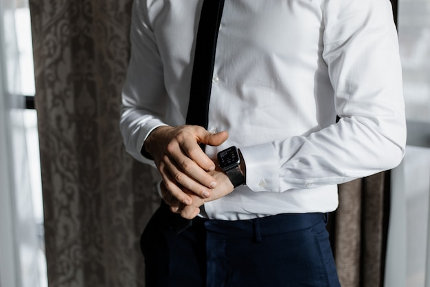 Free Photo elegant man dressed in a white shirt and a tie with a smart watch