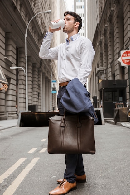 Free photo elegant man drinking on street