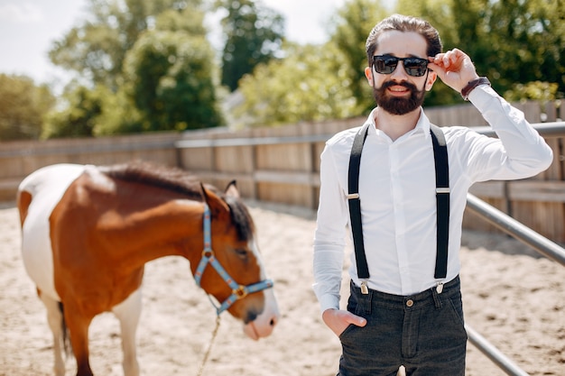 Free photo elegant man standing next to horse in a ranch