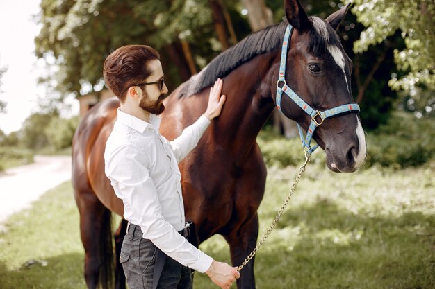 Elegant man standing next to horse in a ranch