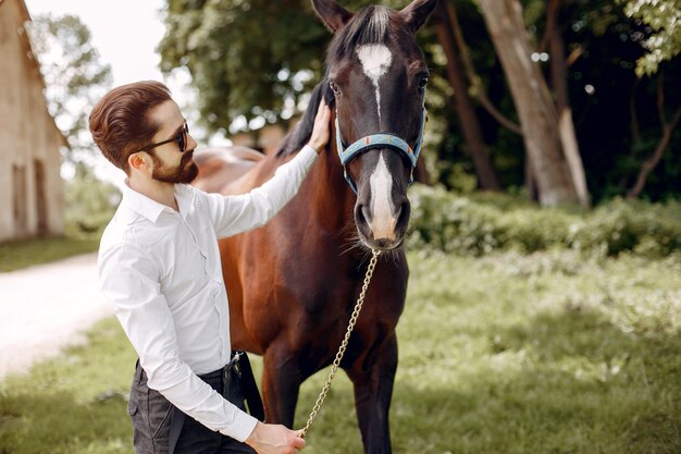 Elegant man standing next to horse in a ranch