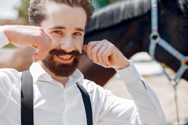 Free photo elegant man standing next to horse in a ranch