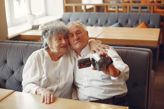 Elegant old couple in a cafe using a camera