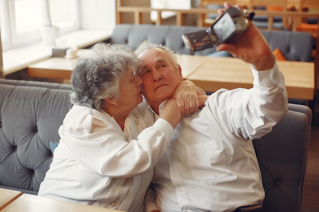 Elegant old couple in a cafe using a camera