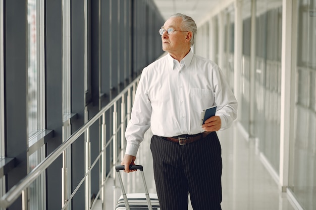 Elegant old man at the airport with a suitcase