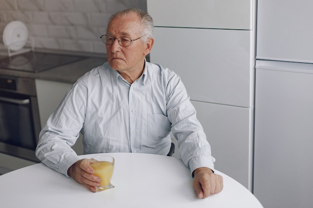 Free photo elegant old man at home with orange juice