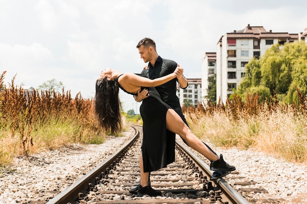 Free photo elegant romantic couple tangoing on the rail track