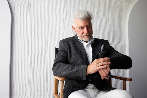 Free Photo elegant senior man posing in suit and checking his watch