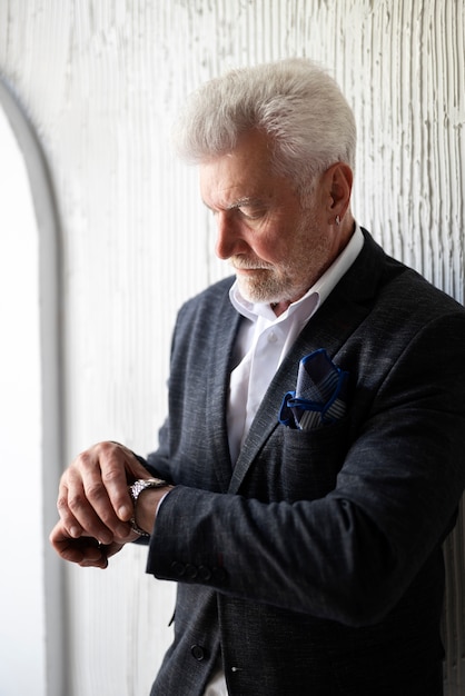 Free Photo elegant senior man posing in suit and checking his watch