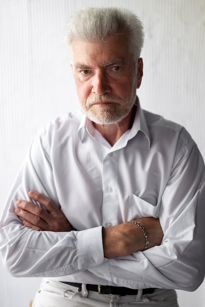 Free photo elegant senior man posing in white shirt