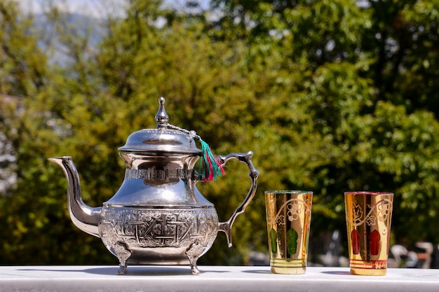 Free photo elegant silver teapot with golden glasses