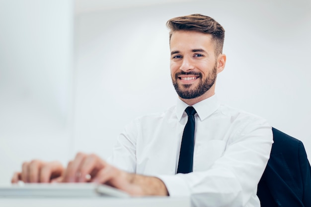 Free photo elegant smiling man typing on a computer