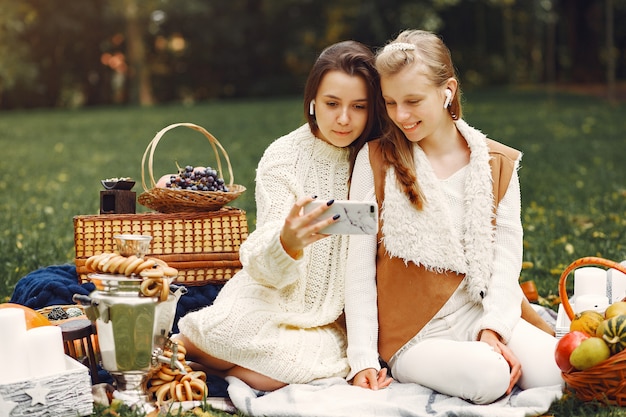 Free photo elegant and stylish girls sitting in a autumn park