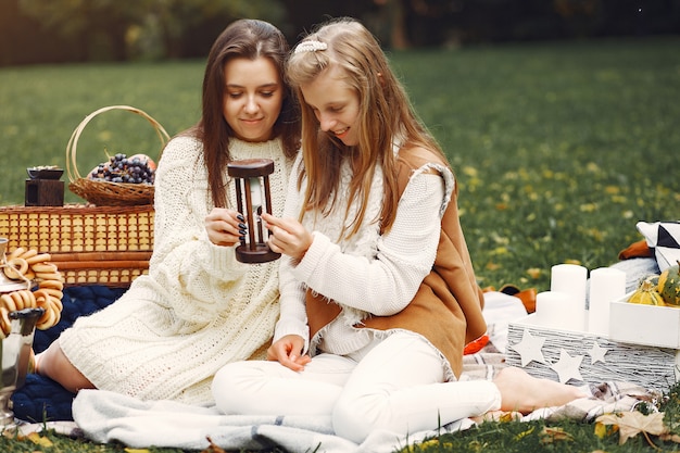 Free photo elegant and stylish girls sitting in a autumn park