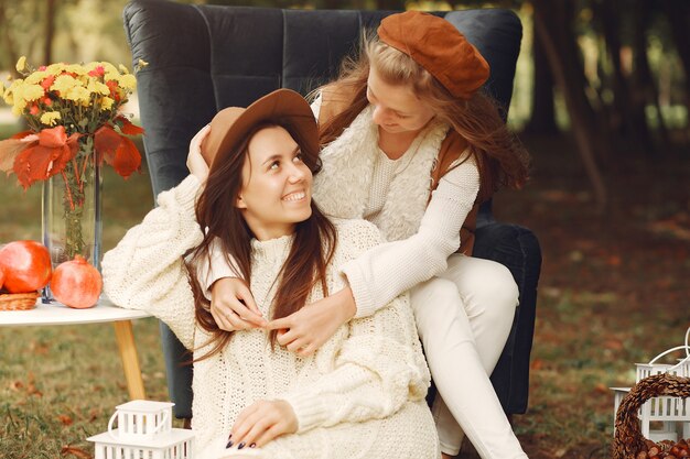 Elegant and stylish girls sitting on a chair in a park