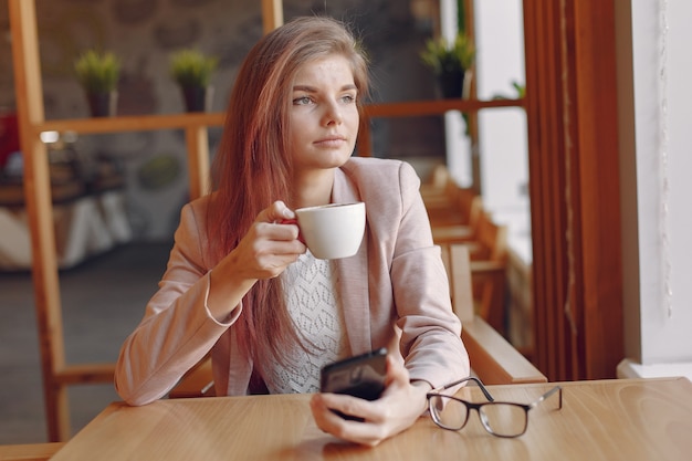 Elegant woman in a pink jacket spending time in a cafe