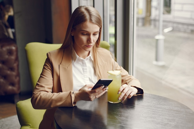 Elegant woman sitting at the table with cocktail and phone