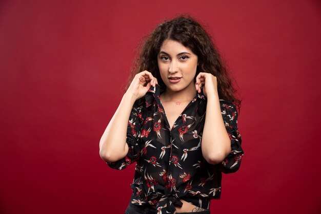 Elegant woman with curly hair standing.