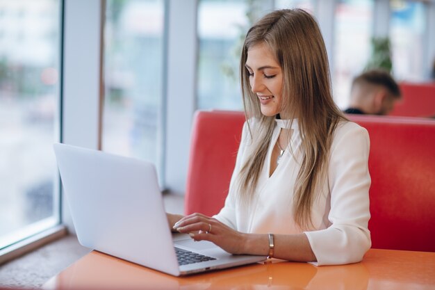 Elegant woman with smiling face typing on her laptop