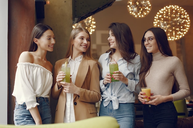 Elegant women standing in a cafe and drinking a cocktails