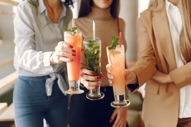 Elegant women standing in a cafe and drinking a cocktails