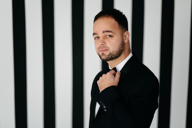 Elegant young handsome man in classic black costume. Studio fashion portrait.