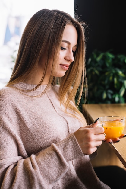 Free photo elegant young woman holding cup of drink at bar counter in cafe