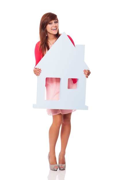 Elegant young woman holding house sign