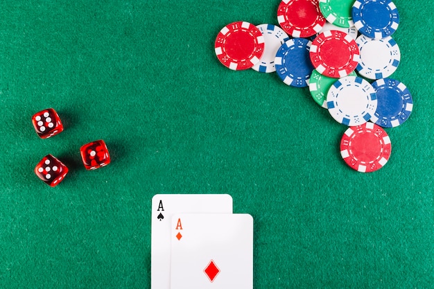 Elevated view of ace playing cards; dice and chips on poker table