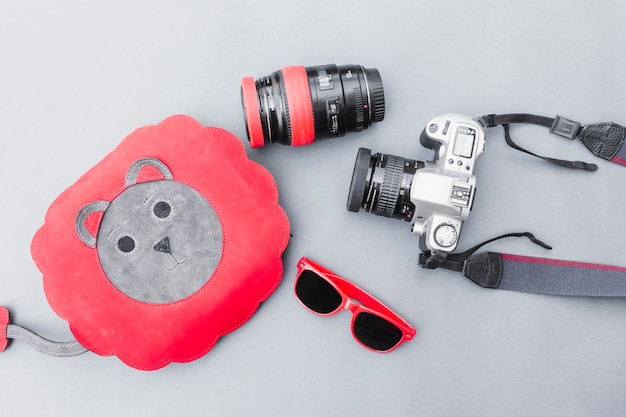 Free Photo elevated view of bag, sunglasses and dslr camera on grey background