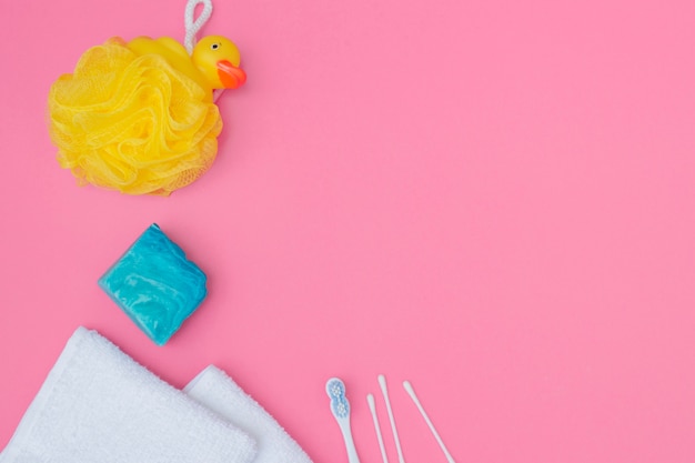 Elevated view of bath sponge; soap; cotton swab and towel on pink background