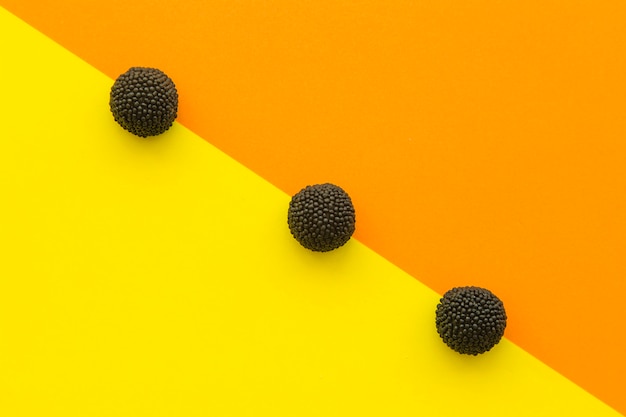 Free photo elevated view of blackberry candies in a row on colorful background