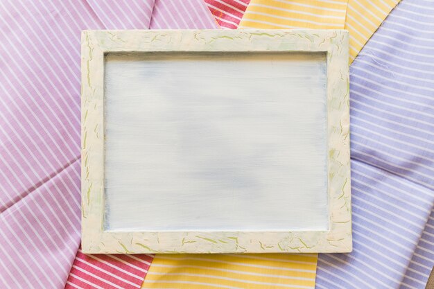 Elevated view of blank frame on colorful stripes pattern textiles