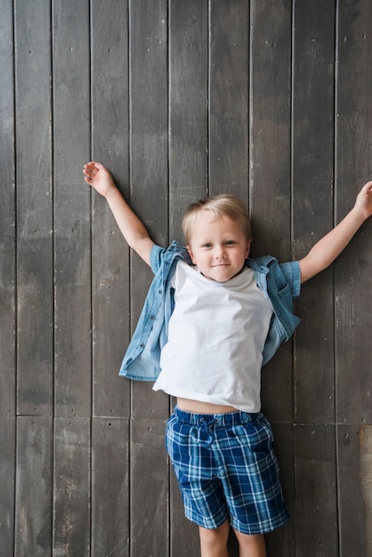 Free photo an elevated view of boy lying on wooden floor