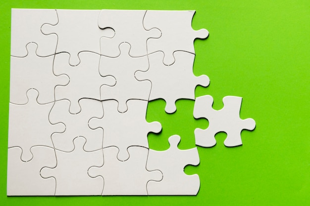 Elevated view of cardboard puzzle on green background